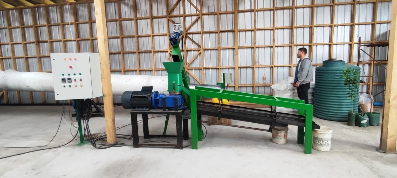 Peletizadora industrial Proplanta instalada en galpón, con tablero de control, motorreductor y cinta transportadora, junto a bolsas de pellet.